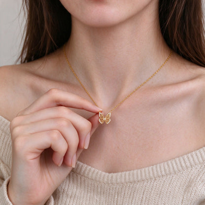 Woman holding the Aurelia gold butterfly pendant between her fingertips