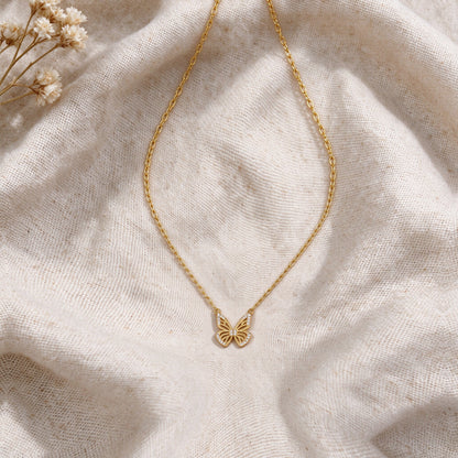 Aurelia gold butterfly necklace laid flat on natural linen