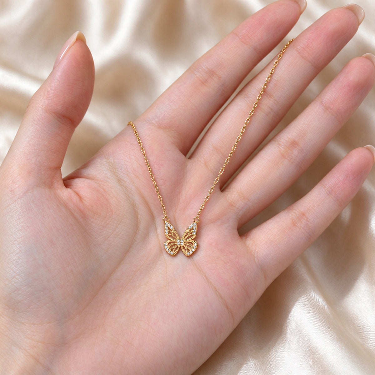 Aurelia gold butterfly necklace in an open palm showing its 14 mm pendant size
