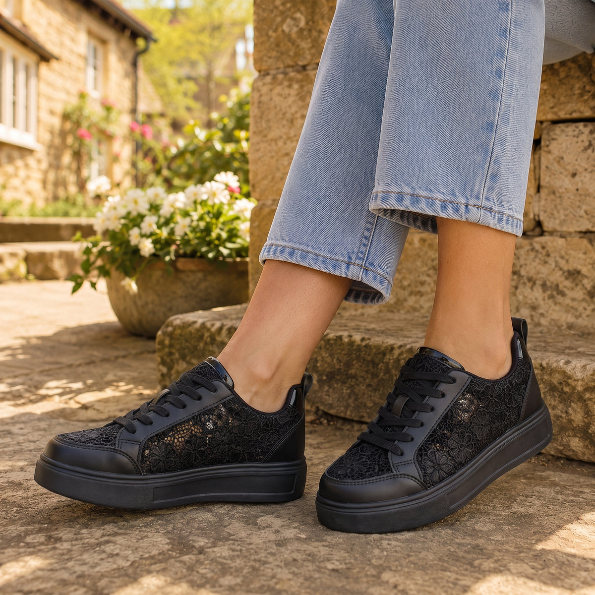 Clara floral lace trainers in black worn outdoors