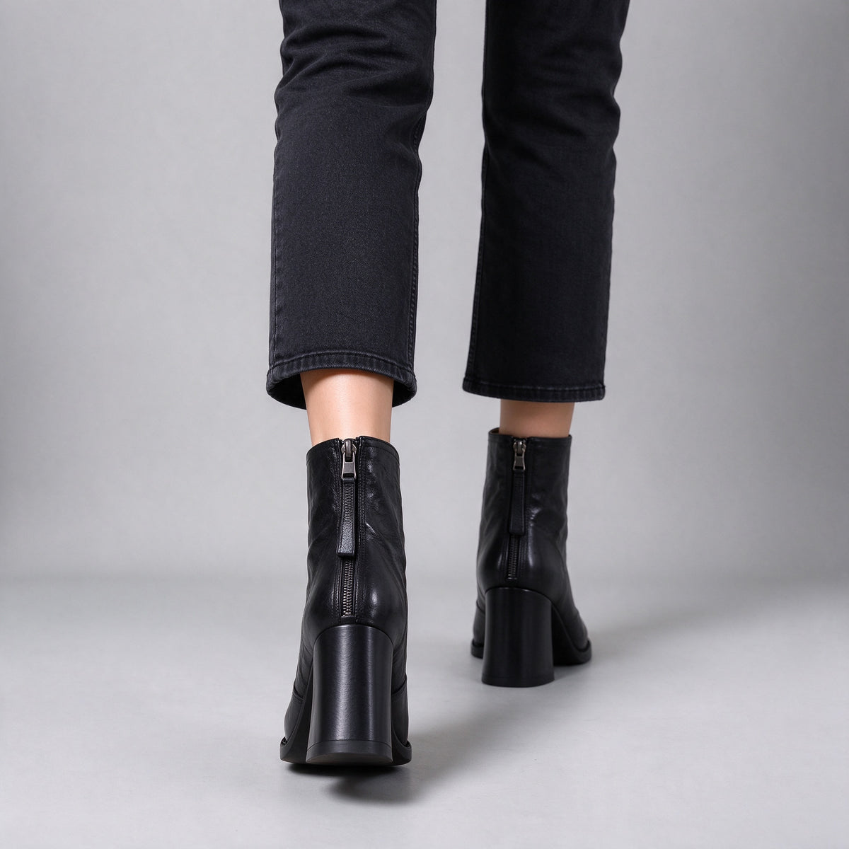 Livia black ankle boots from behind while walking, back zips and block heels