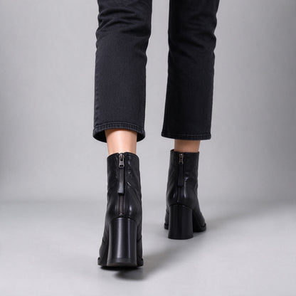 Livia black ankle boots from behind while walking, back zips and block heels