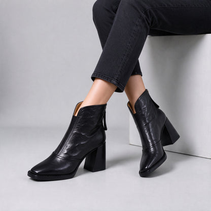 Livia black leather ankle boots worn seated with crossed ankles